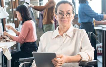 Lady in wheelchair in front of people working on craft items