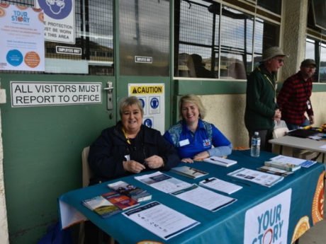 Two people sitting at table laid with Your Story promotional material