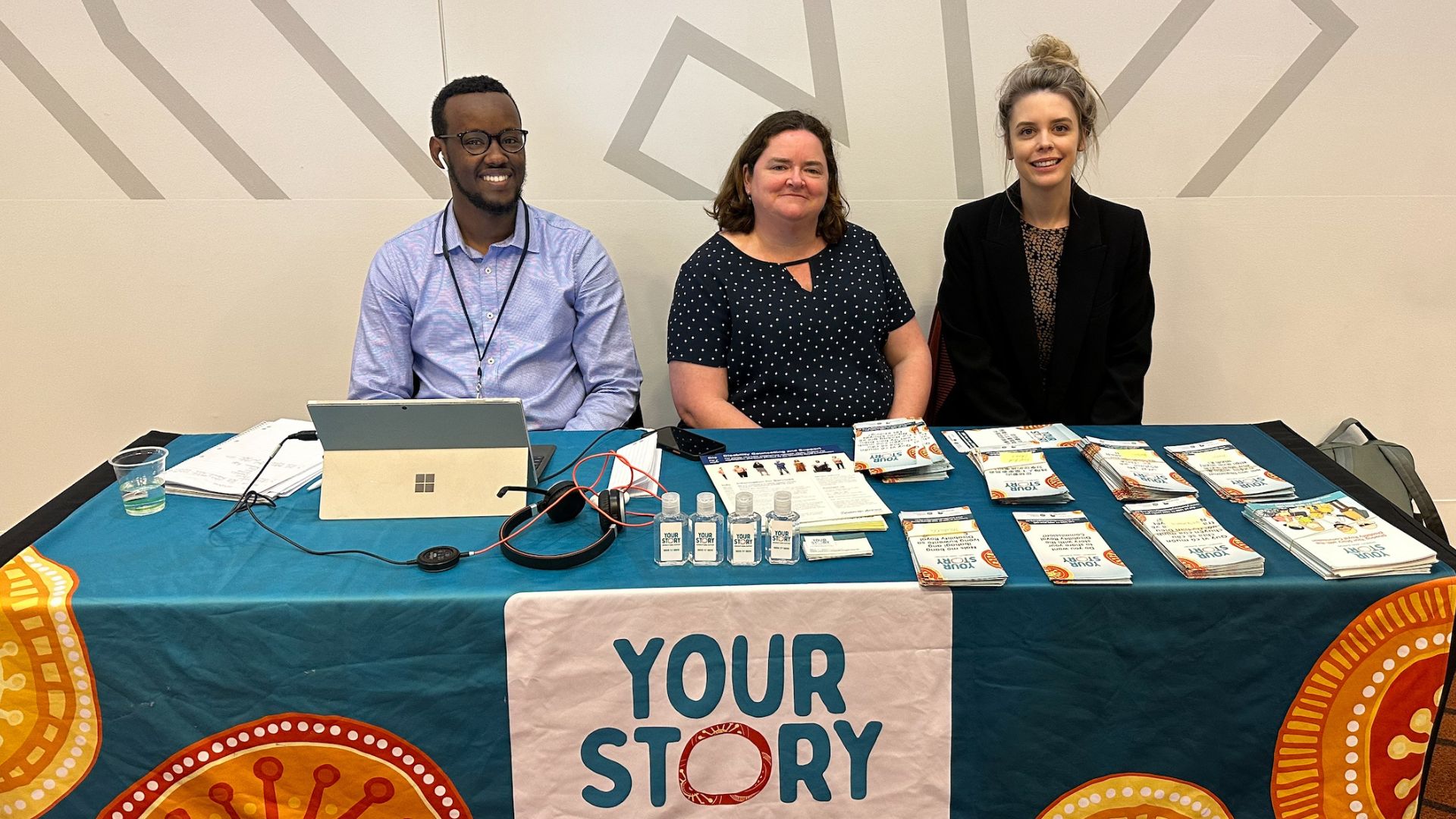 Three smiling people - a man and two women - sit behind a table for Your Story Disability Legal Support