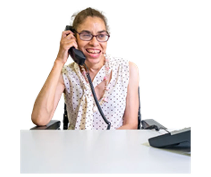 Woman smiling and sitting at a table with phone receiver to her ear