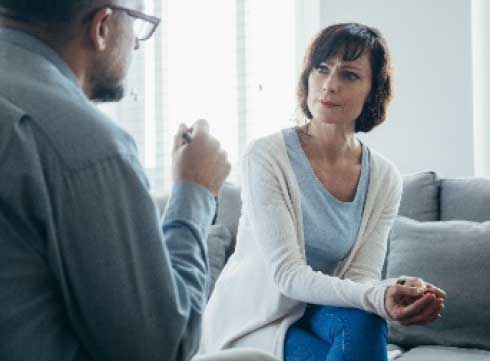 middle aged lady sitting on couch listing to man talking