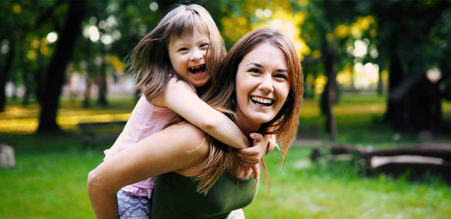 Sandra giving a child with Down syndrome a piggy back